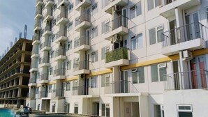 Un immeuble résidentiel à plusieurs étages, doté de balcons, d’une piscine et de climatiseurs.