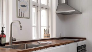 Una cocina moderna con un lavamanos de acero inoxidable, armarios blancos y un piso a cuadros blanco y negro.