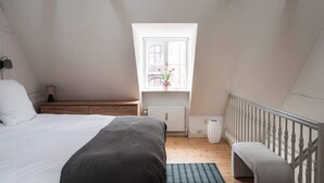Ein Schlafzimmer mit einem Bett, einer Bank, einem Fenster mit Blick und einer Heizung.