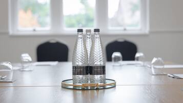 Una mesa de conferencias con tres botellas de agua con la etiqueta "Harrogate Spring Water" y una jarra de cristal.