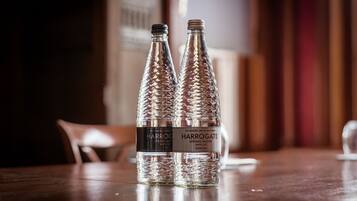 Zwei Harrogate Spring Water Flaschen auf einem Holztisch in einem Raum mit unscharfem Hintergrund.