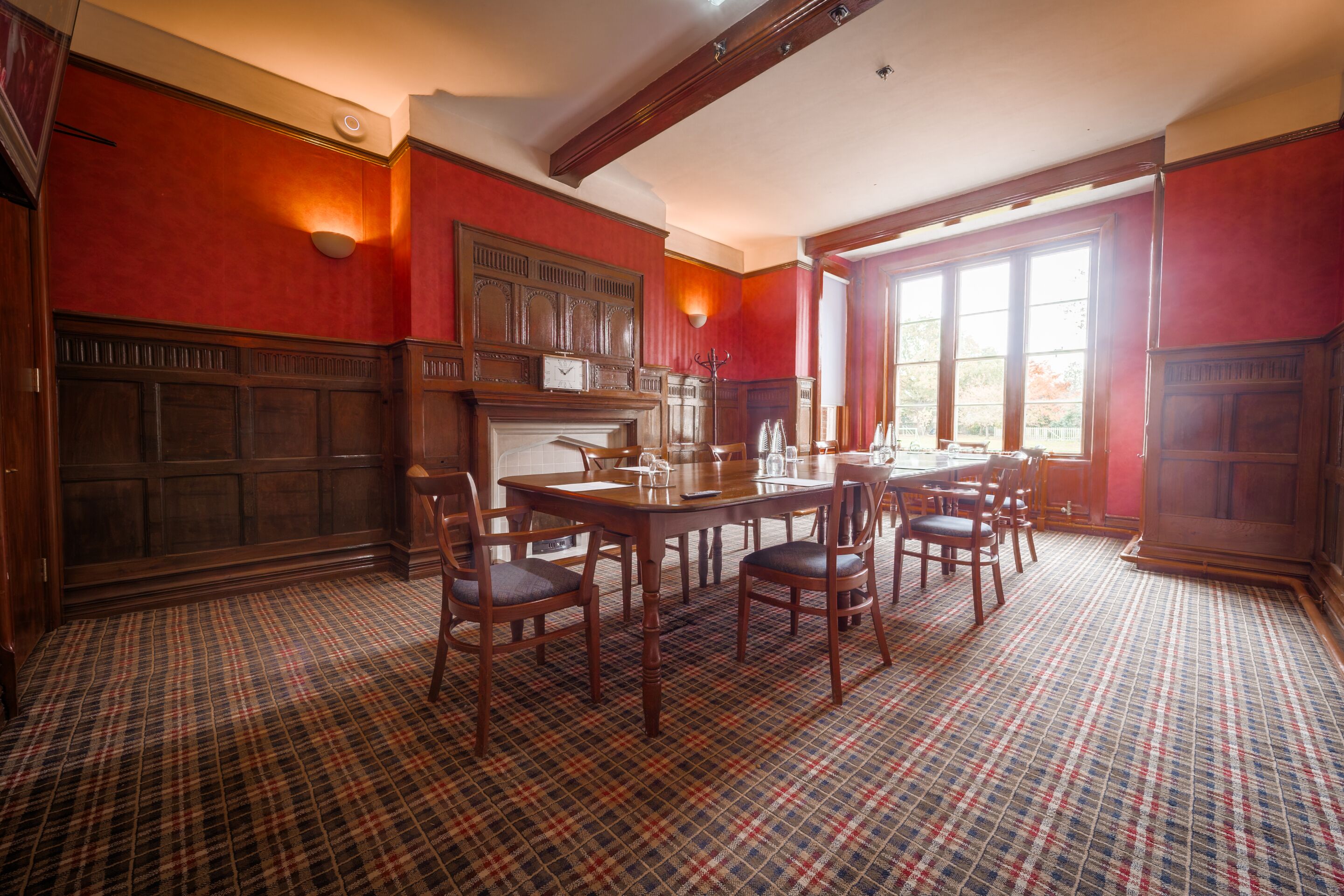 A dining room with a plaid carpet, wooden furniture, and a fireplace.