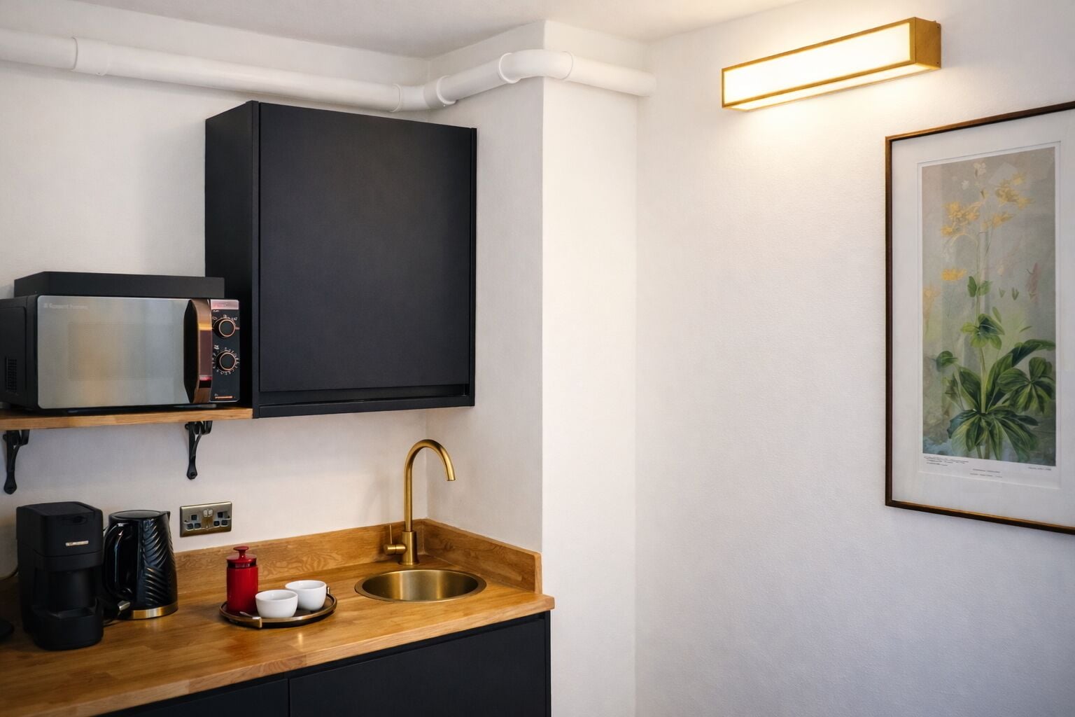 A compact kitchen with a microwave, coffee maker, and sink.