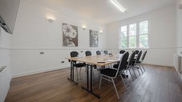 A conference room with a long table, black chairs, and two wall-mounted light fixtures.