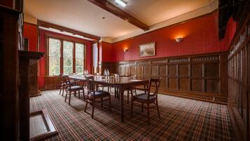 A dining room with a plaid carpet, wooden table, chairs, and a window with a view.