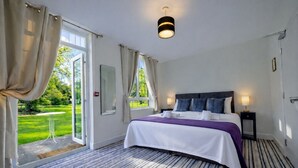 Une chambre d’hôtel avec un grand lit, une vue sur un jardin et un luminaire moderne au plafond.