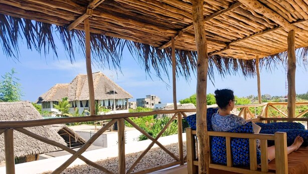 Een houten terras met rieten dak met uitzicht op een resort.