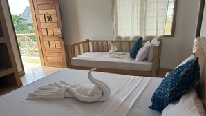 Een hotelkamer met een groot bed, een kleiner bed en een balkon met houten leuning.