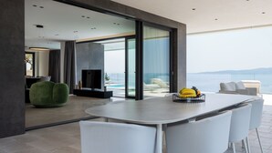 A modern living room with a large glass door leading to a balcony with a view of the sea. - Villa Brela-Rogac 3 (Baska Voda)
