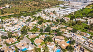 An aerial view of a residential area with houses, roads, and a large industrial complex in the background. - Villa Gabriella - Charming villa in great location (Guia)