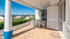 A balcony with a table and chairs, a view of the surrounding buildings, and a door with shutters. - Villa Gabriella - Charming villa in great location (Guia)