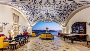 A luxurious lobby with a view of the sea, ornate ceiling, and a central seating area.