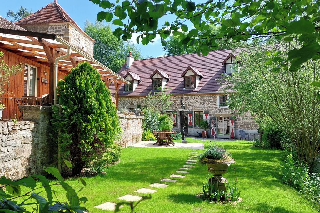 A stone house with a wooden porch, a stone wall, and a well-maintained garden with a stone pathway.