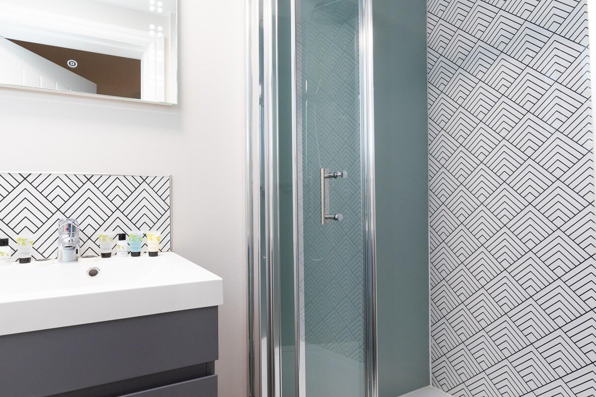 A bathroom with a white sink, a mirror, and a shower with a glass door.