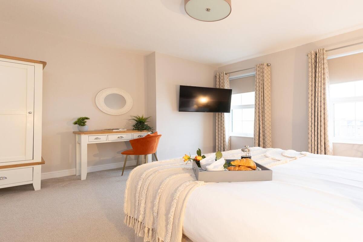 A hotel room with a bed, a desk, a TV, and a window with curtains.