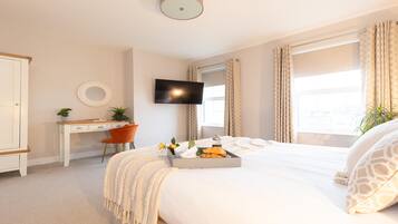 A hotel room with a bed, a desk, a TV, and a window with curtains.