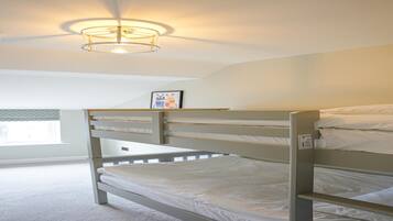 Quarto com beliche, luminária no teto, quadro na parede e janela com persianas.