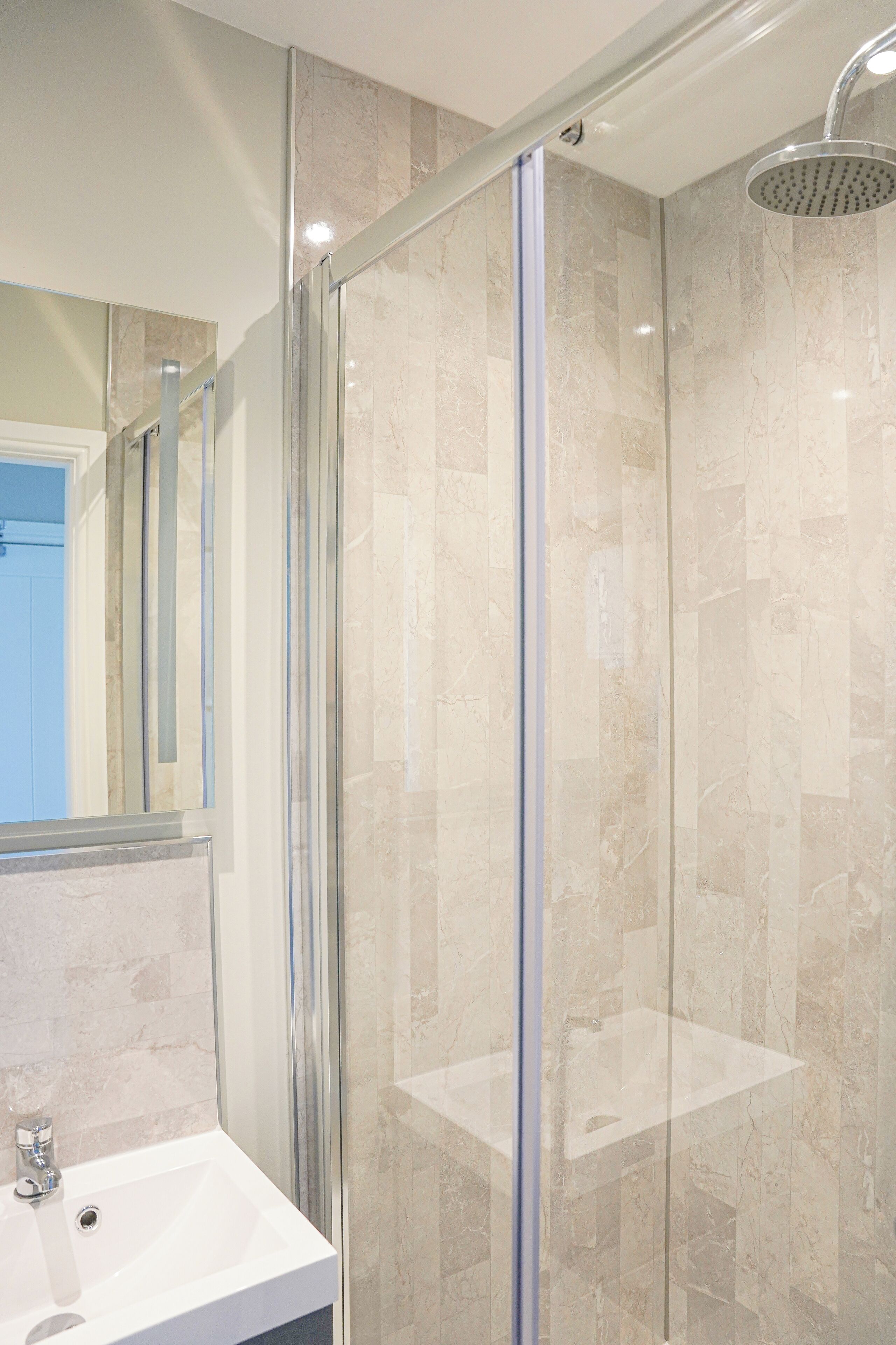 A modern bathroom with a glass-enclosed shower, a sink, and a mirror.