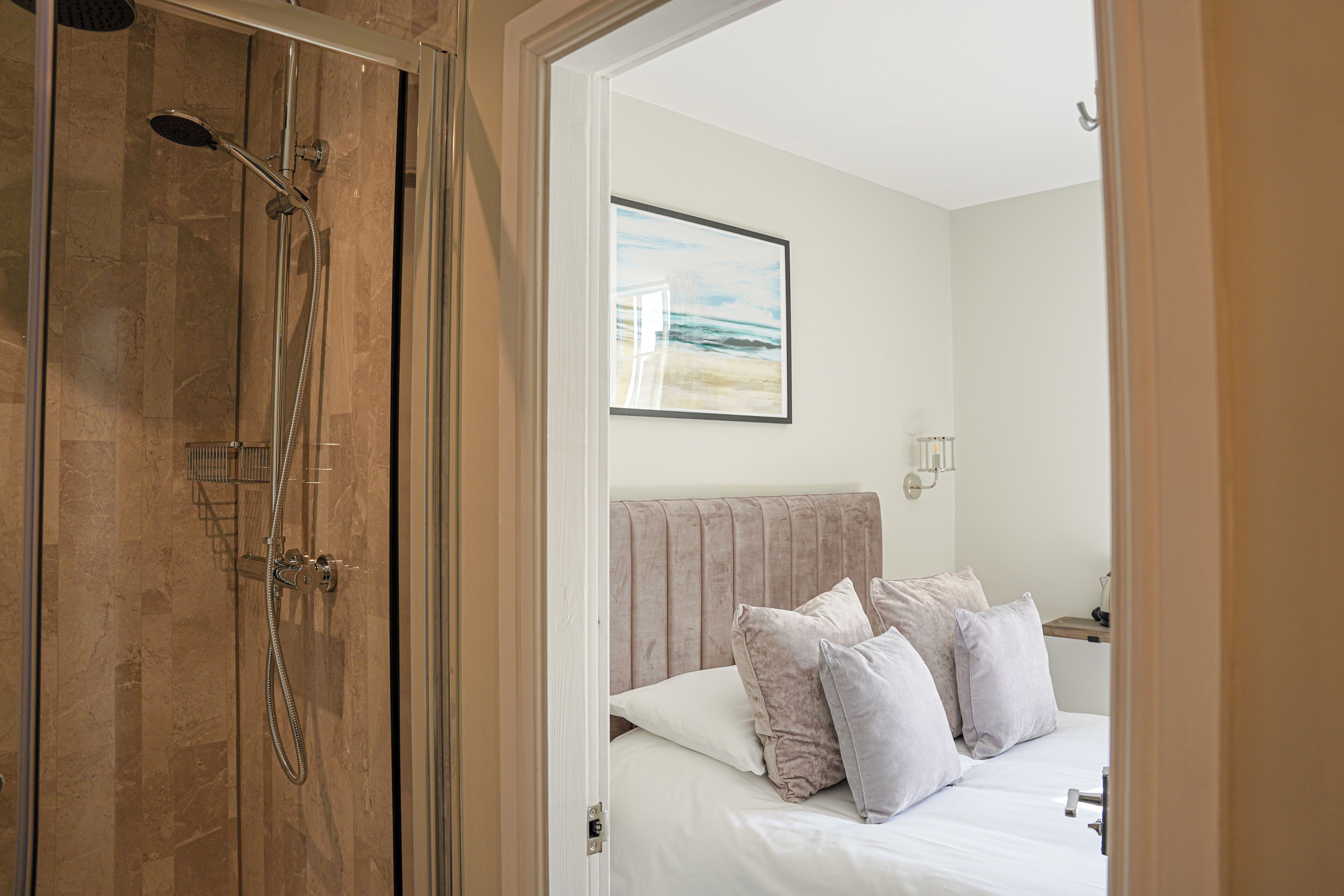 A room with a bed, a shower, and a framed picture on the wall.