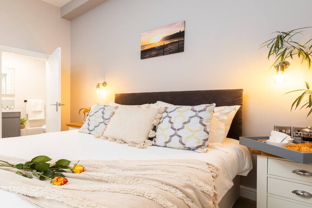 A well-lit bedroom with a bed, bedside table, and a wall-mounted lamp.