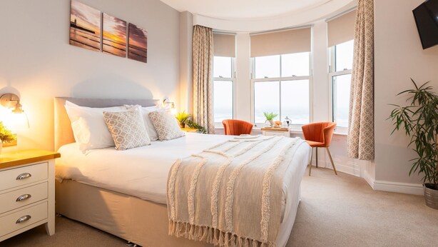 A bedroom with a large bed, a desk, two chairs, a TV, and a window with curtains. - The Clarence Gardens Hotel, BW Signature Collection (Scarborough)