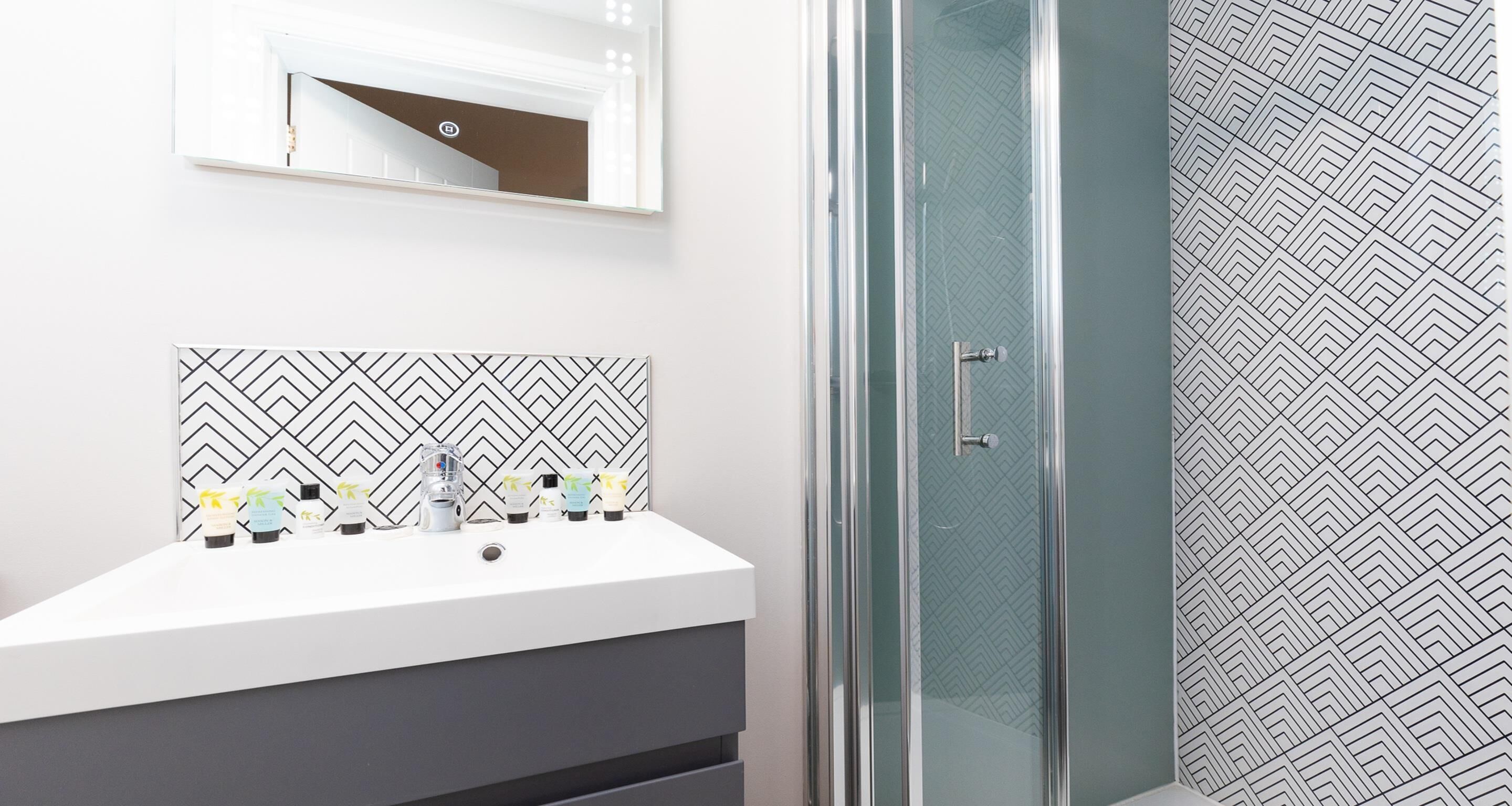 A bathroom with a white sink, a mirror, and a shower with a glass door.