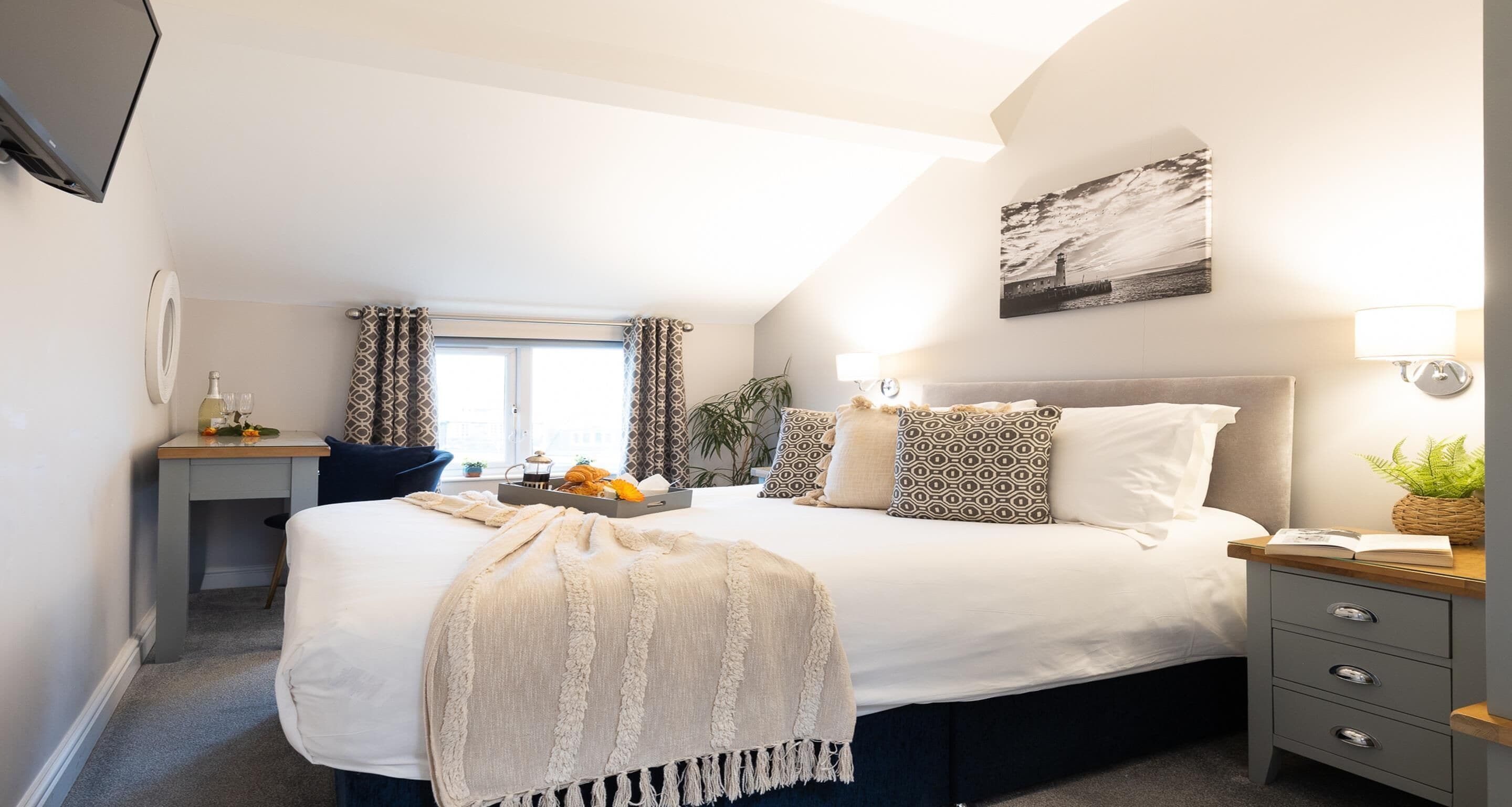 Une chambre à coucher avec un grand lit, des tables de chevet, un bureau et une fenêtre avec des rideaux.