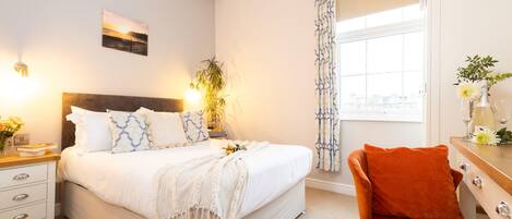 A bedroom with a bed, bedside table, lamp, and a chair.