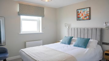 Un dormitorio con cama, ventana con persiana estampada, radiador, lámpara de pared y un cuadro.