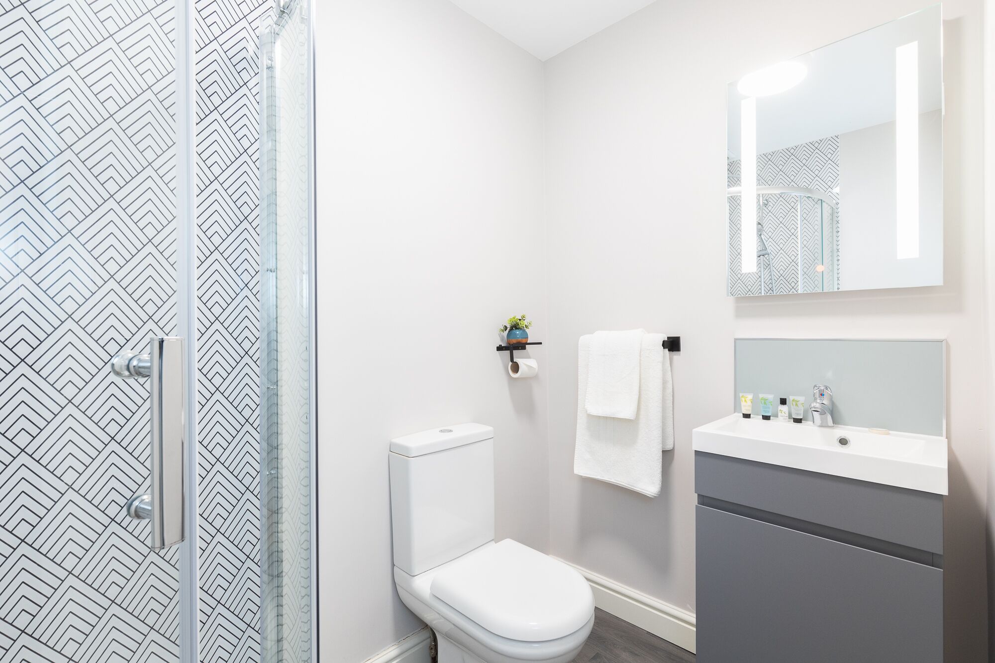 A modern bathroom with a shower, toilet, and sink.