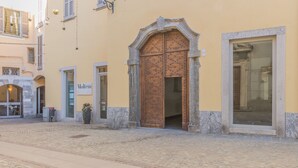 A cobblestone street with a building featuring a large wooden door and a sign that reads "Motel". - Casa Lenora in Bellano (Bellano)