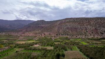 A mountainous landscape with terraced fields and a cloudy sky.