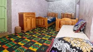Una habitación con piso estampado, una cama con colcha estampada, un armario de madera y una puerta verde.