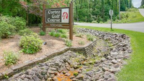 A sign for Cortez Golf Course with a stone pathway and greenery. - Hot Springs Village Condo on the Green (Hot Springs)