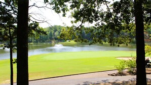 A golf course with a pond, surrounded by trees and a clear sky. - Hot Springs Village Condo on the Green (Hot Springs)