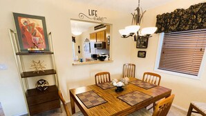 A dining area with a wooden table, chairs, and a decorative mirror. - Hot Springs Village Condo on the Green (Hot Springs)