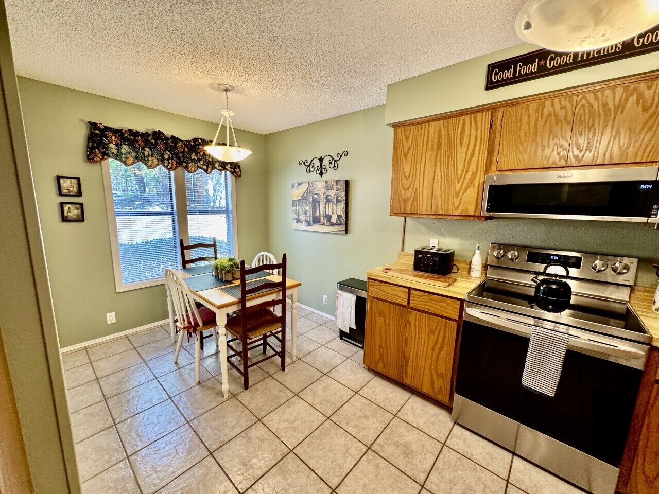 A kitchen with wooden cabinets, a microwave, an oven, and a dining area with chairs and a table.