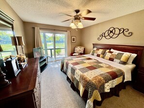 Une chambre à coucher avec un grand lit, un ventilateur de plafond, un bureau et une chaise.