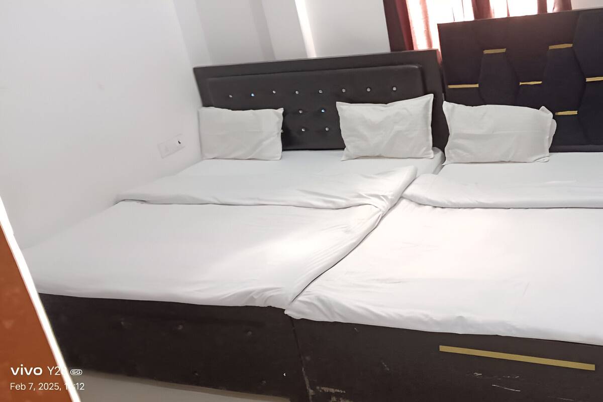 A double bed with white bedding and a dark headboard with a geometric pattern.
