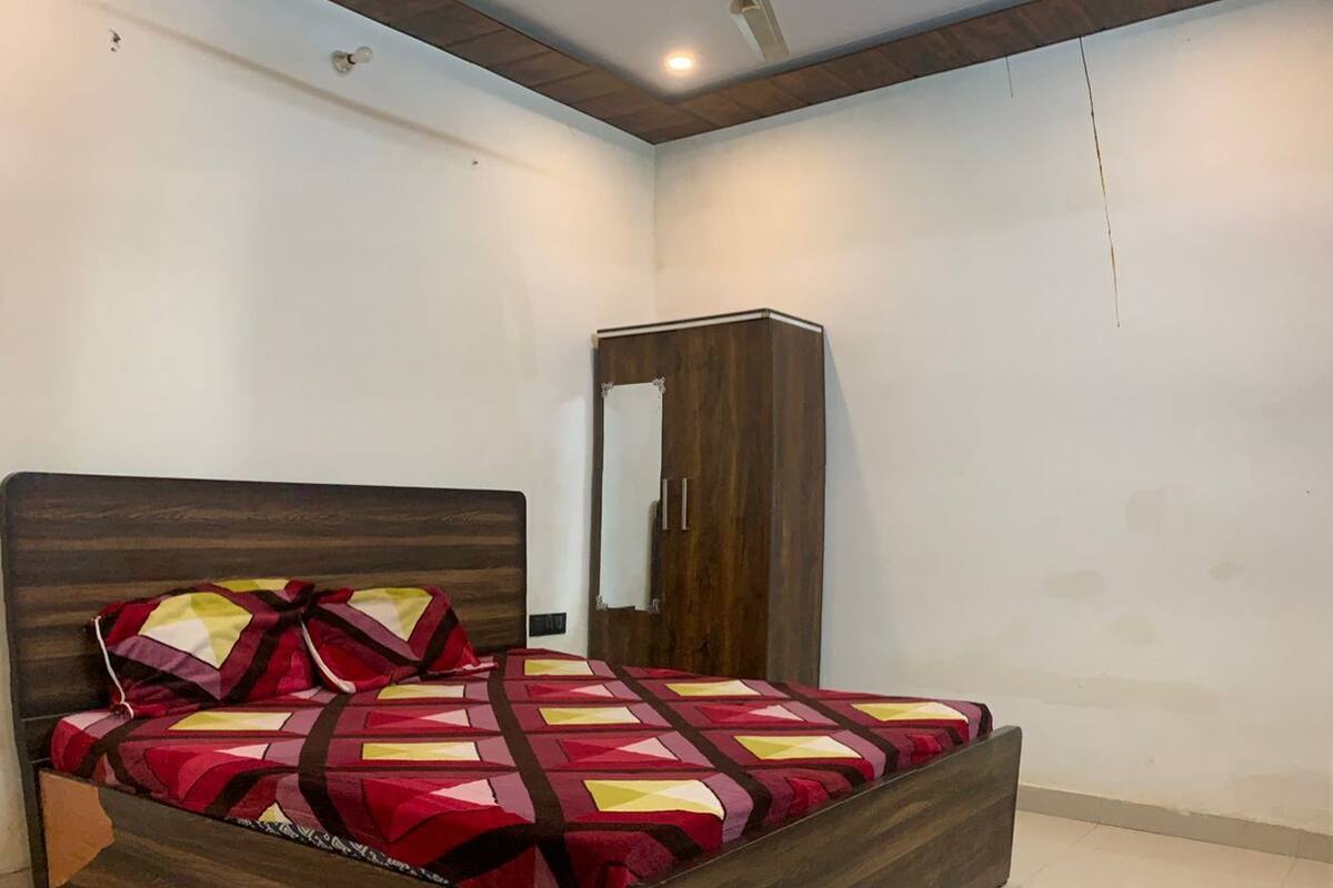 A bedroom with a wooden bed, a wardrobe, a ceiling fan, and recessed lighting.