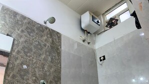 Een badkamer met toilet, douche en boiler.