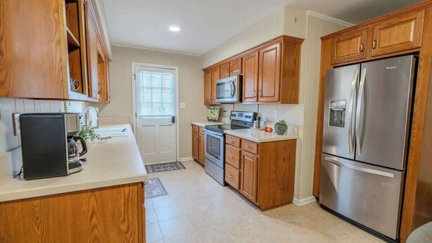 A kitchen with wooden cabinets, stainless steel appliances, and a white countertop.