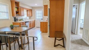 A modern kitchen with wooden cabinets, a dining table with chairs, and a small island.
