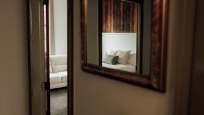 A room with a white sofa and a mirror reflecting a wooden wall.