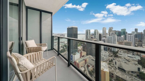 Ein Balkon mit Korbstühlen und Blick auf die Stadt.