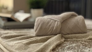A neatly folded towel on a textured fabric surface, likely a bed or lounge area. - Urban Chic: 2BR + FREE Parking (Birmingham)