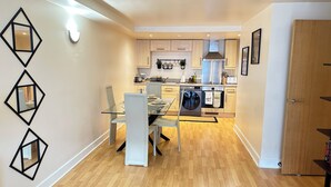 A modern kitchen with a dining area, wooden flooring, and light-colored cabinets. - Urban Chic: 2BR + FREE Parking (Birmingham)