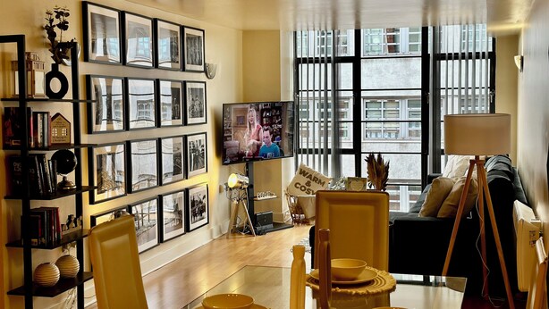 A living room with a bookshelf, a television, a sofa, and a dining area with a table and chairs. - Urban Chic: 2BR + FREE Parking (Birmingham)