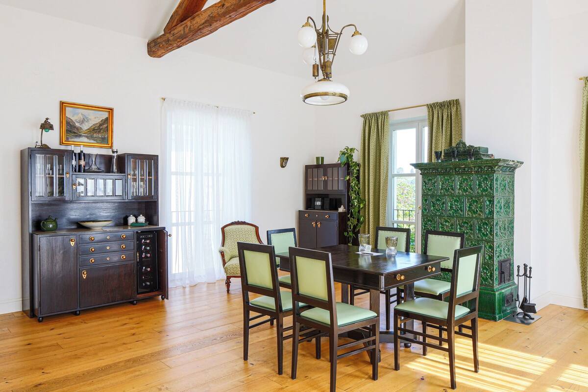 A dining area with a wooden table and chairs, a green cabinet, and a chandelier.