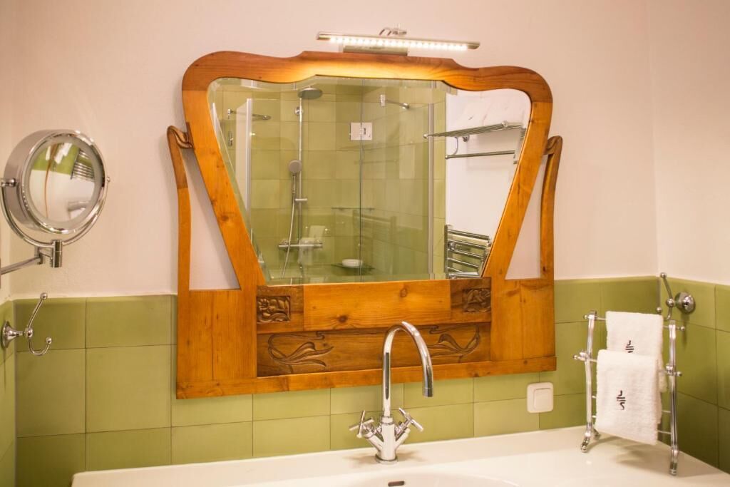 Un baño con espejo de marco de madera, lavabo blanco y un perchero para toallas.